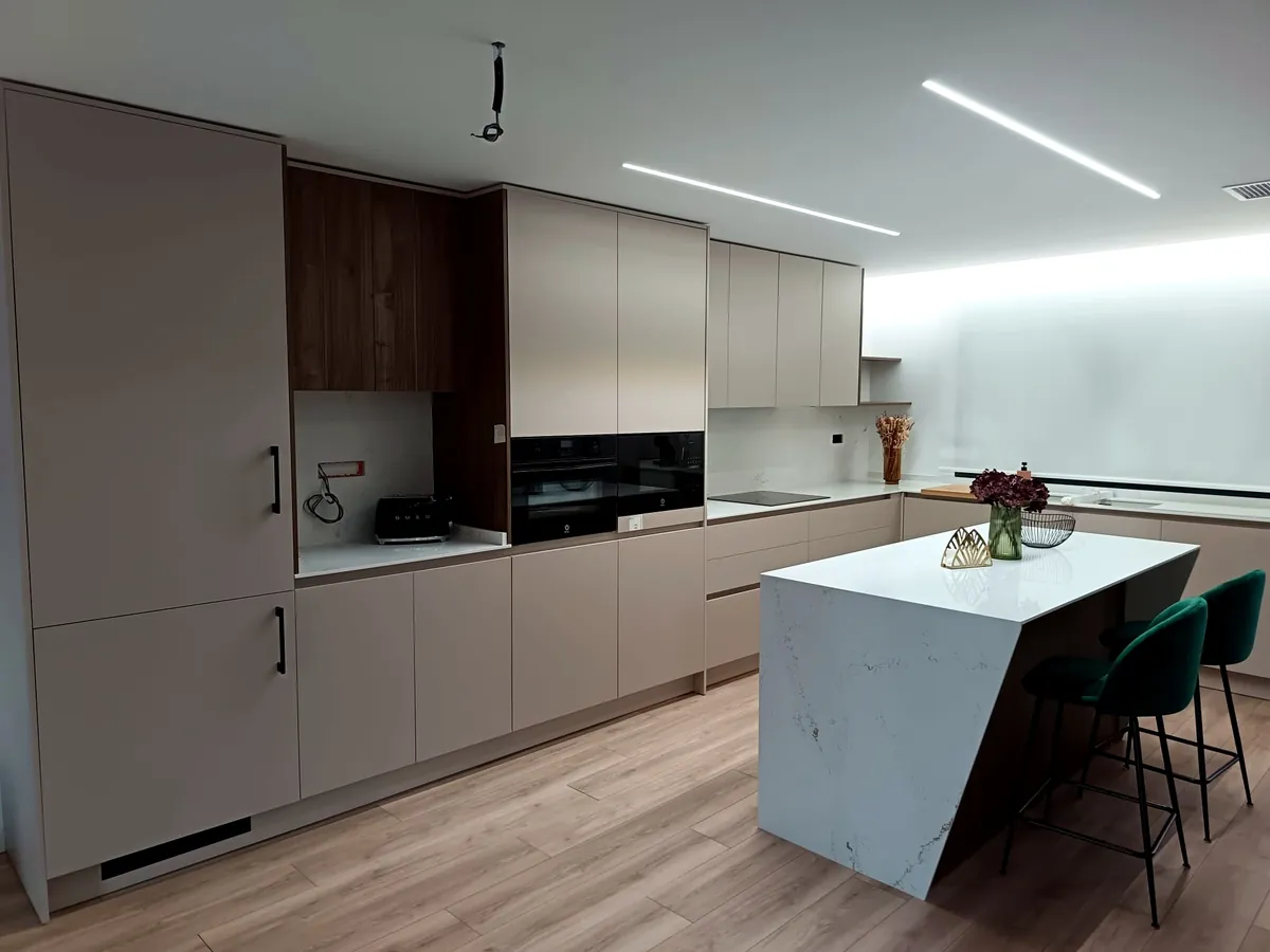 Cocina completa con isla en mármol y taburetes verdes