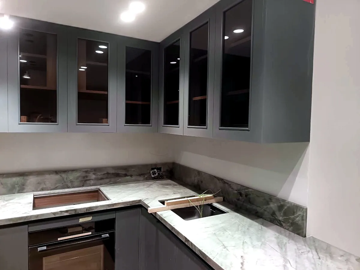 Cocina con muebles altos acristalados y encimera en mármol verde
