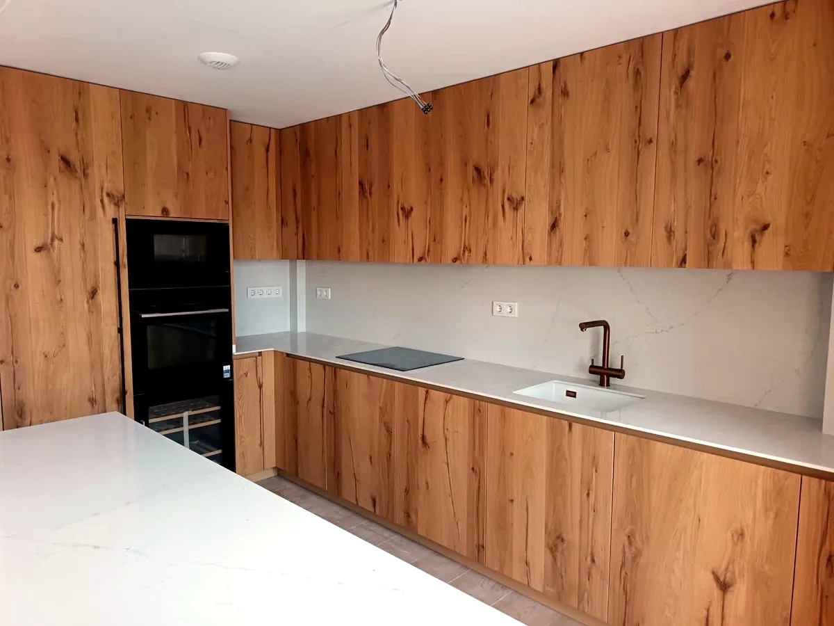 Cocina en madera de roble con encimera blanca y grifo de cobre