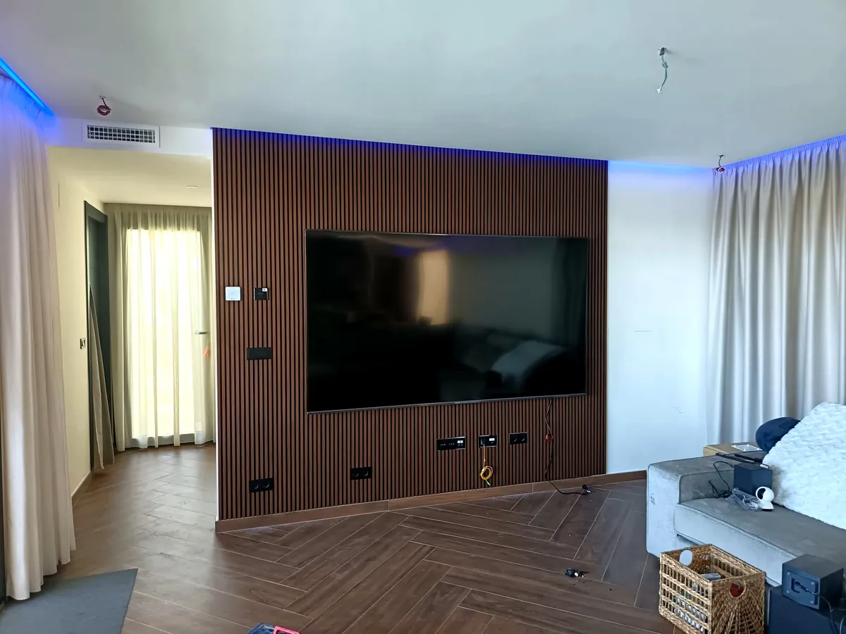 Salón reformado con panel de madera ranurada e iluminación LED integrada